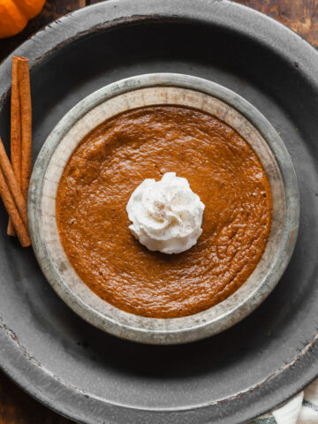 single serving crustless pumpkin pie in a small pie dish with a dollop of whipped cream on top