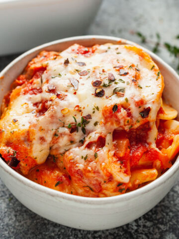 a bowl of baked ravioli topped with tomato sauce and melted cheese