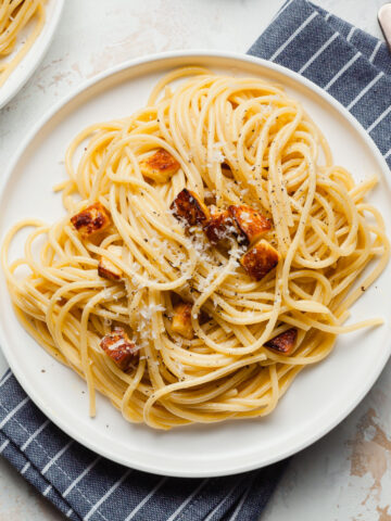 halloumi carbonara on a plate with a blue striped napkin underneath