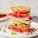 a hummus sandwich on a white plate cut open and stacked on top of each other