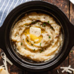 cheesy crock pot mashed potatoes topped with butter and chives