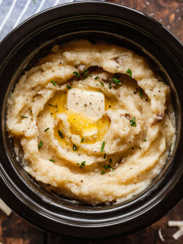 cheesy crock pot mashed potatoes topped with butter and chives