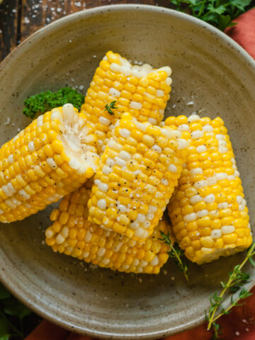 pieces of steamed corn on a plate topped with salt and pepper