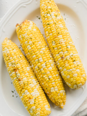 three ears of air fryer corn on the cob on a plate
