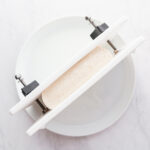 Tofu in a tofu press in a shallow bowl.