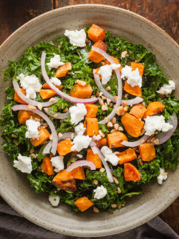 Kale and Sweet Potato Salad in a bowl next to a blue napkin and a fork.