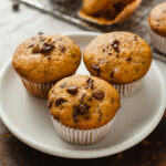 Three Mini Pumpkin Chocolate Chip Muffins on a round white plate.