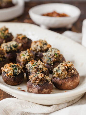 Side view of stuffed mushrooms on a white platter.