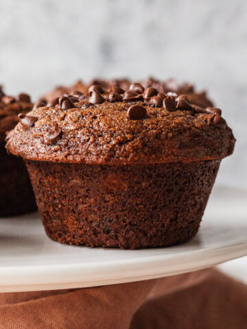 A close up of one double chocolate banana muffin on a cake stand.
