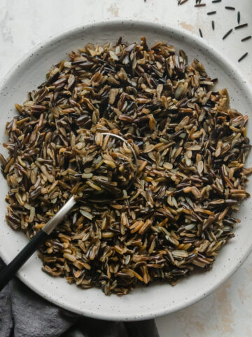 Top view of Instant Pot Wild Rice in a white bowl with a spoon sticking out of it.
