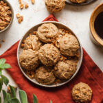 Maple nut breakfast cookies on a plate next to a mug of coffee and a bowl of nuts.