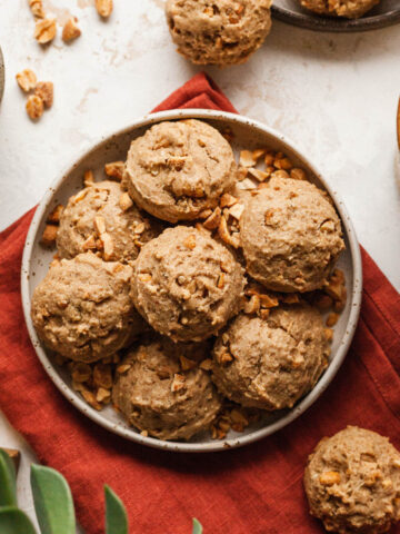 Maple nut breakfast cookies on a plate next to a mug of coffee and a bowl of nuts.