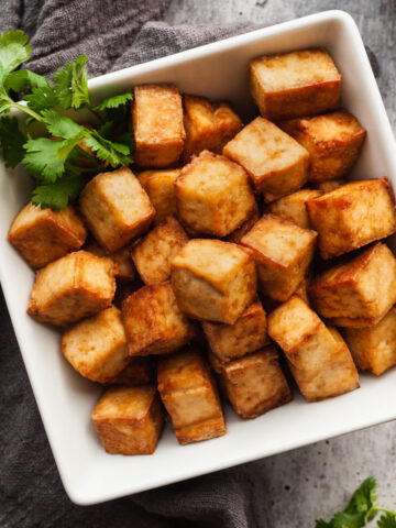 Crispy tofu in a white square bowl garnished with parsley.