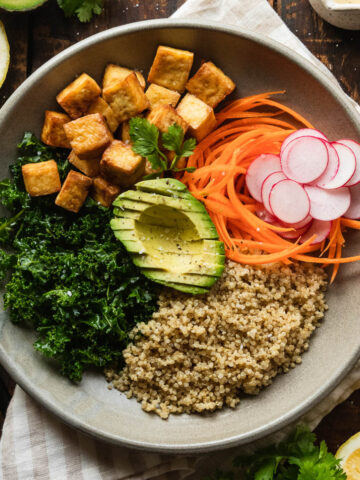 Vegan tofu bowl on a checked napkin next to lemons.