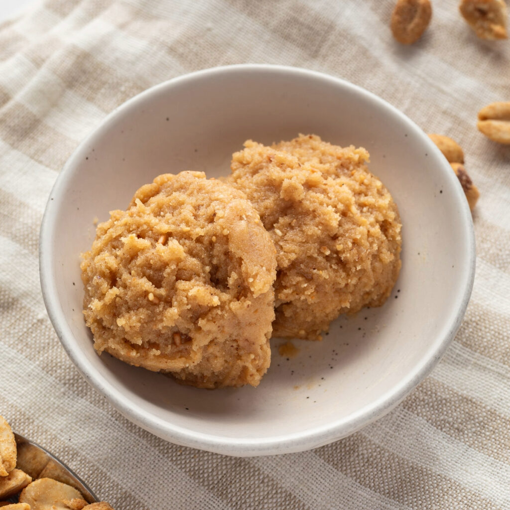 Two scoops of edible peanut butter cookie dough in a small white bowl.
