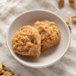 Two scoops of edible peanut butter cookie dough in a small white bowl.