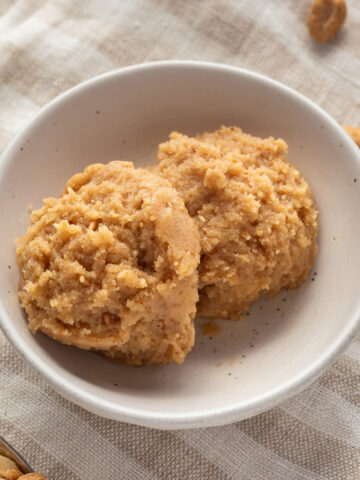 Two scoops of edible peanut butter cookie dough in a small white bowl.