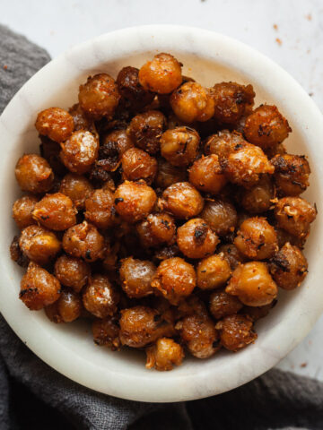 Crispy spicy roasted chickpeas in a small bowl next to a gray cloth napkin.