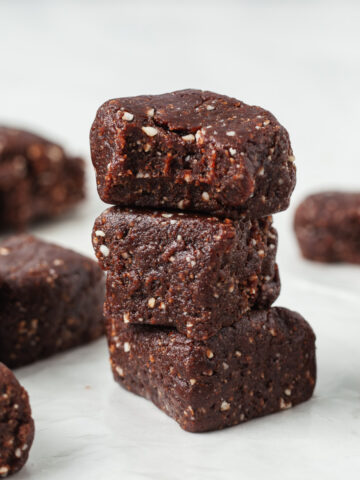 A stack of three larabar mini brownie bites with a bite taken out of the top one.