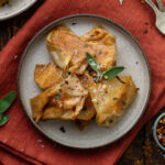 A plate of crispy butternut squash ravioli on a red linen napkin.