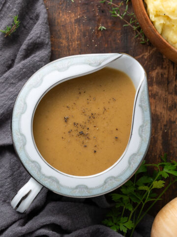 A gravy boat full of vegan gravy topped with black pepper.