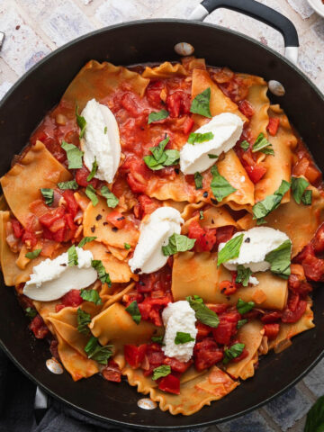 Lasagna in a skillet next to a serving spoon.