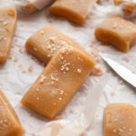 Whiskey salted caramels on a sheet of wax paper topped with pink salt.