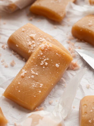 Whiskey salted caramels on a sheet of wax paper topped with pink salt.