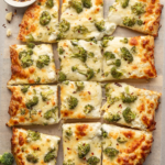 Alfredo pizza topped with broccoli cut into squares.