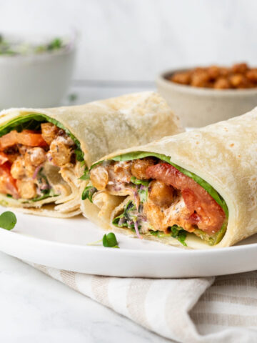 Two halves of a cajun chickpea wrap on a white plate.