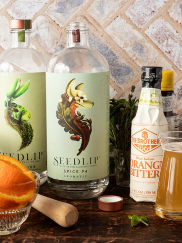 Mocktail ingredients including 2 bottles of Seedlip Spirits, orange bitters, simple syrup, and orange wedges.