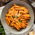 A shallow bowl of penne alla vecchia bettola topped with parmesan cheese and fresh oregano.