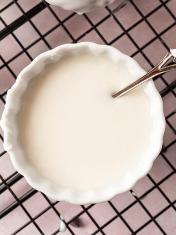 A bowl of vanilla icing with a spoon in it.