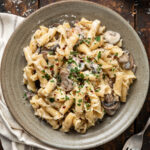 A plate of mushroom alfredo next to a fork.