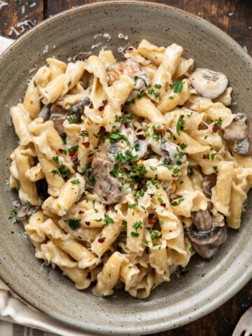 A plate of mushroom alfredo next to a fork.