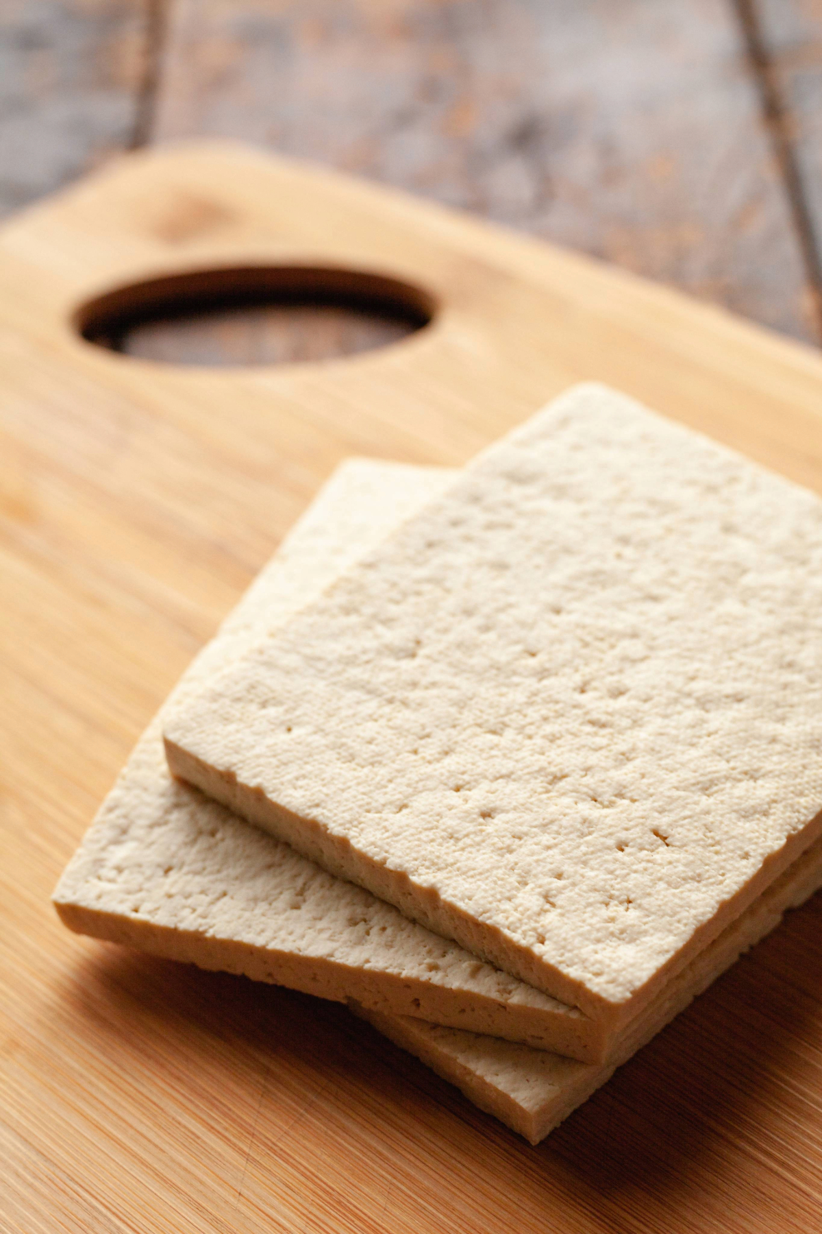 Tofu cut into thin slabs on a cutting board.