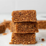Homemade larabars cut into squares and stacked on top of each other.