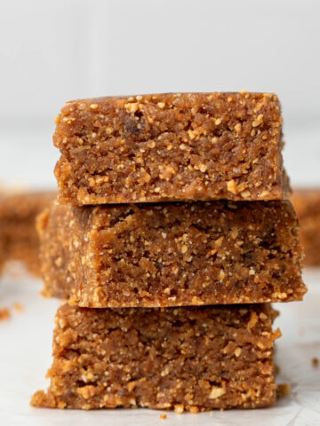 Homemade larabars cut into squares and stacked on top of each other.