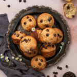 A platter full of chocolate chip zucchini muffins next to a gray linen napkin.