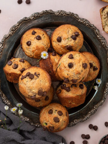 A platter full of chocolate chip zucchini muffins next to a gray linen napkin.