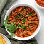 Tofu tinga in a white bowl garnished with cilantro leaves.