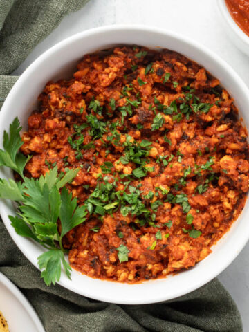 Tofu tinga in a white bowl garnished with cilantro leaves.
