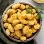 Air fryer gnocchi in a bowl garnished with a sprig of parsley.