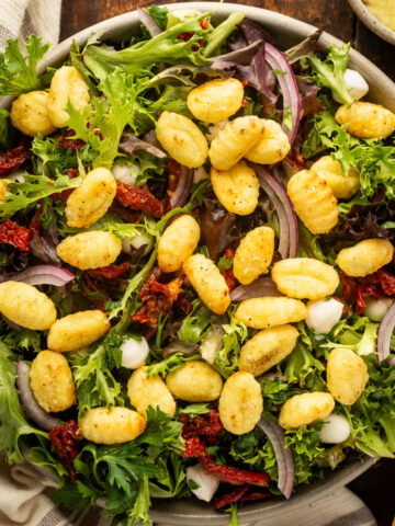 A big bowl of salad with air fryer gnocchi on top.