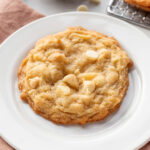 One white chocolate macadamia nut cookie on a white plate.