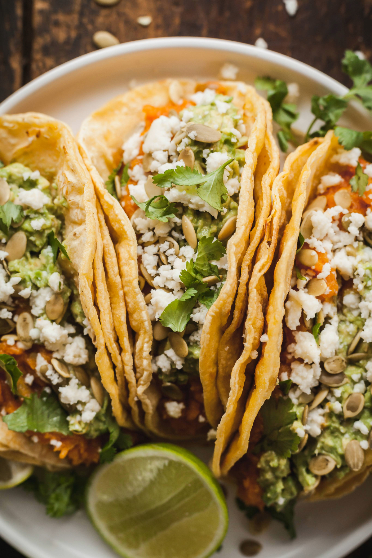 Three mashed sweet potato tacos on a white plate.