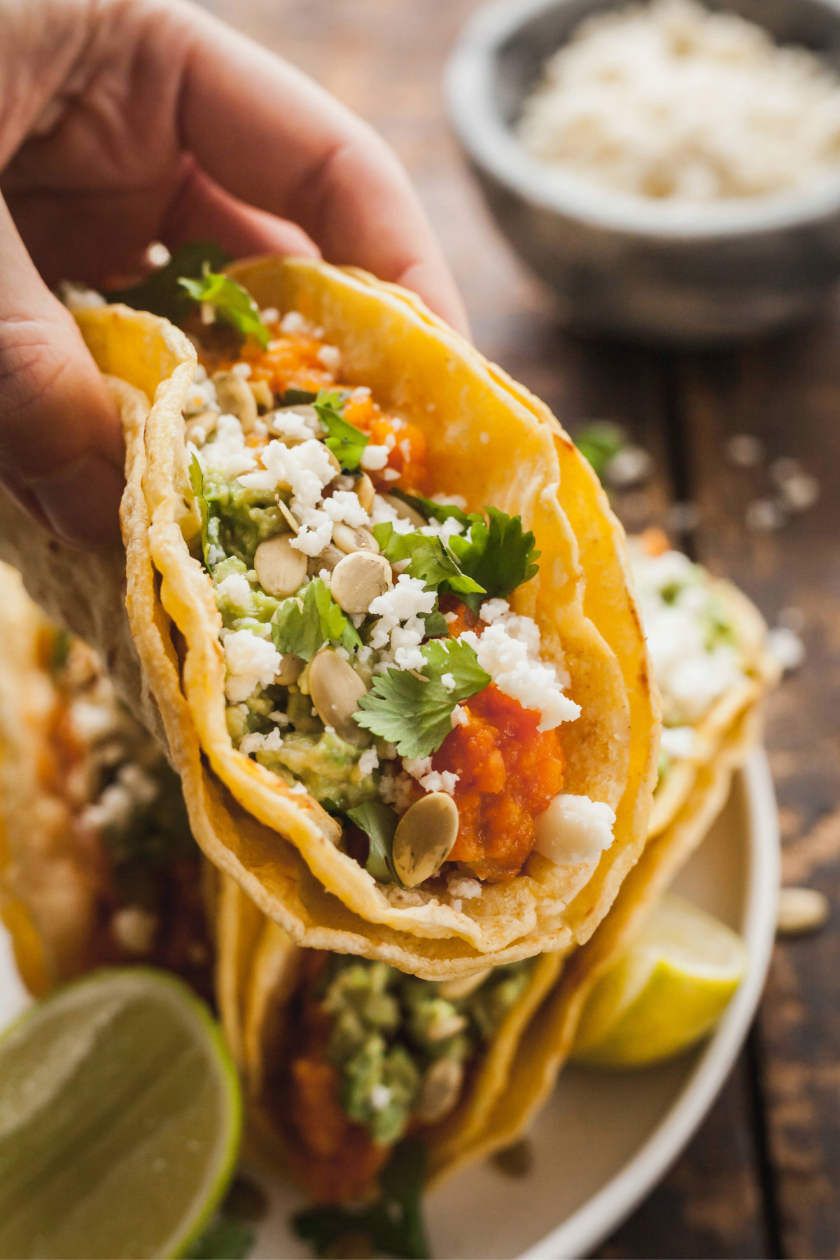 A hand holding up a mashed sweet potato taco.