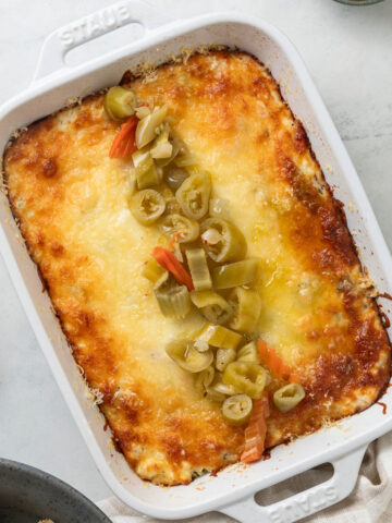Baked giardiniera dip in white casseroled dish.