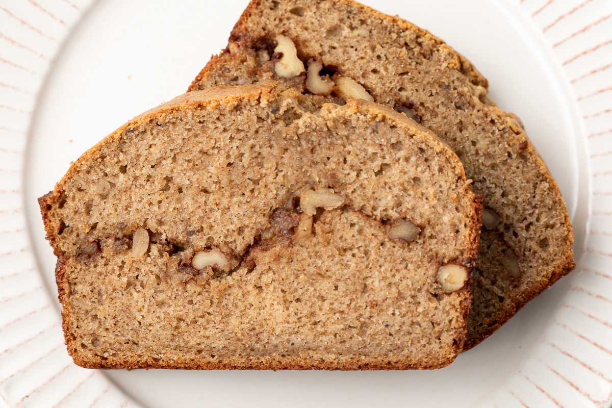 Two slices of cinnamon swirl banana bread on a white plate.