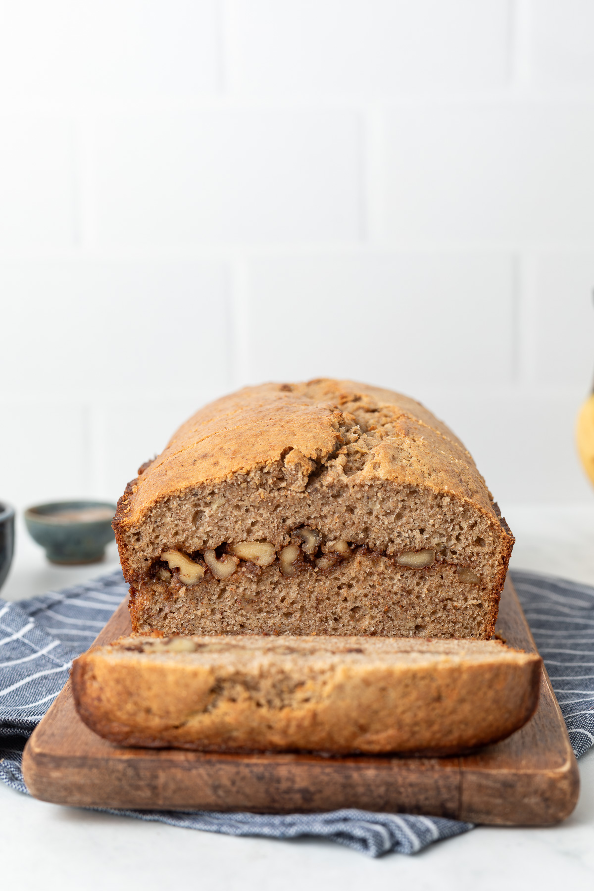 Banana bread loaf with a slice cut off revealing the inside swirl of cinnamon and walnuts,